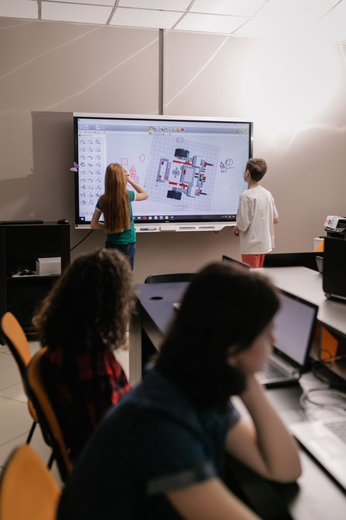 services-03 Kids learning with an interactive board in a modern classroom setting.